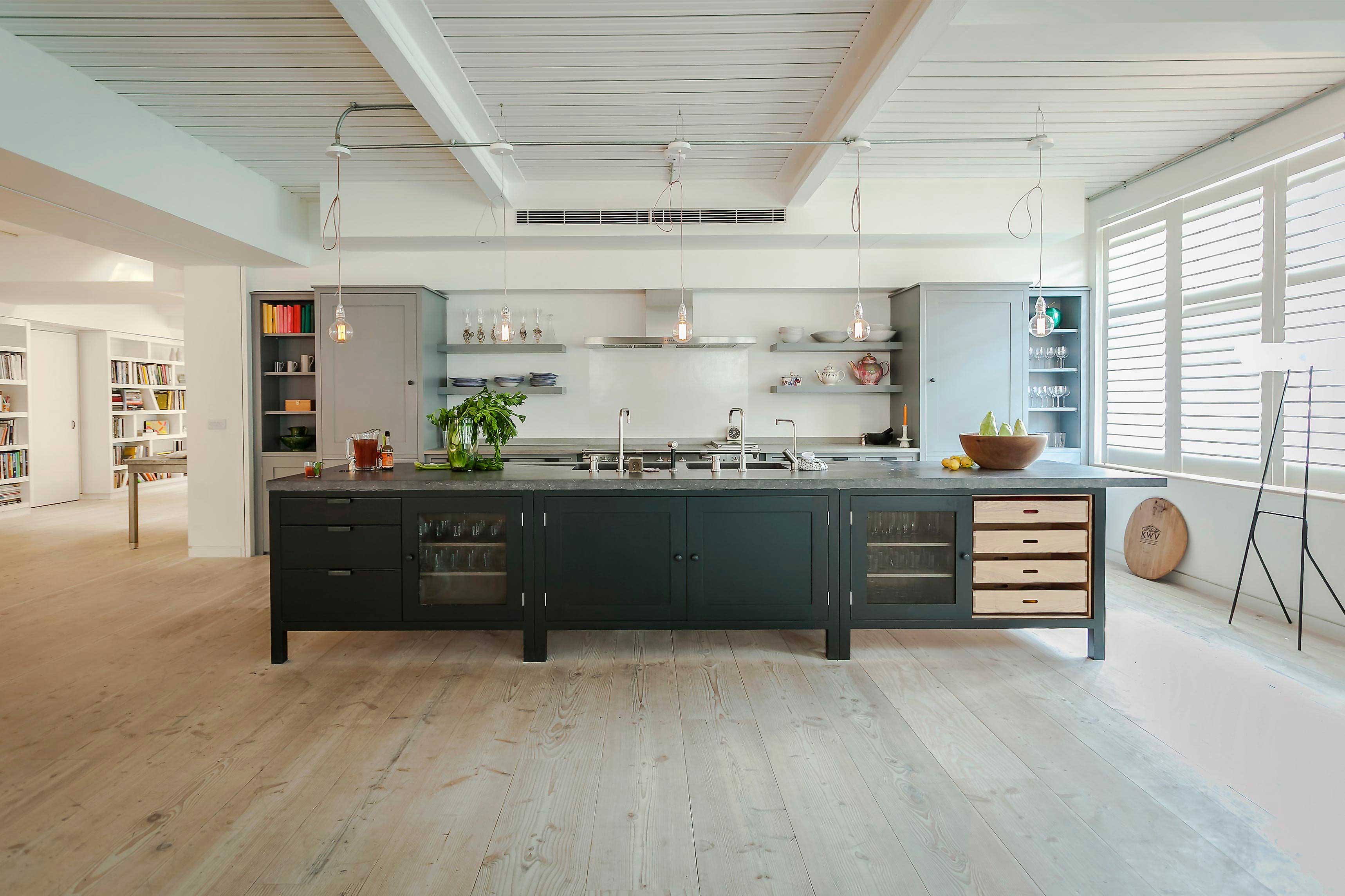  Open-plan London loft kitchen with industrial details, floating grey shelves, and whitewashed walls