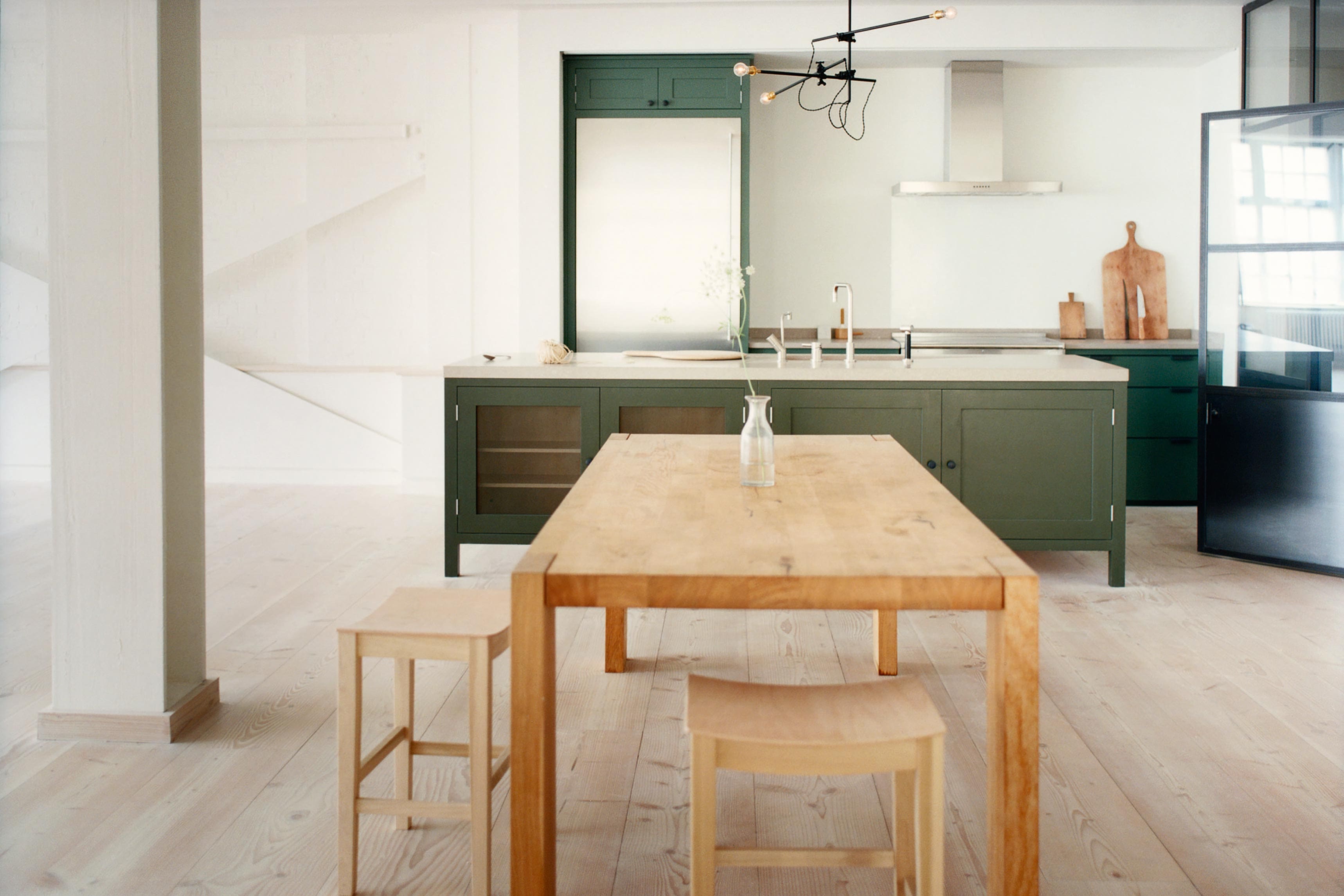  Industrial-style kitchen with Plain English army green cabinetry, Shitake Caesarstone counters, and large wooden worktable.