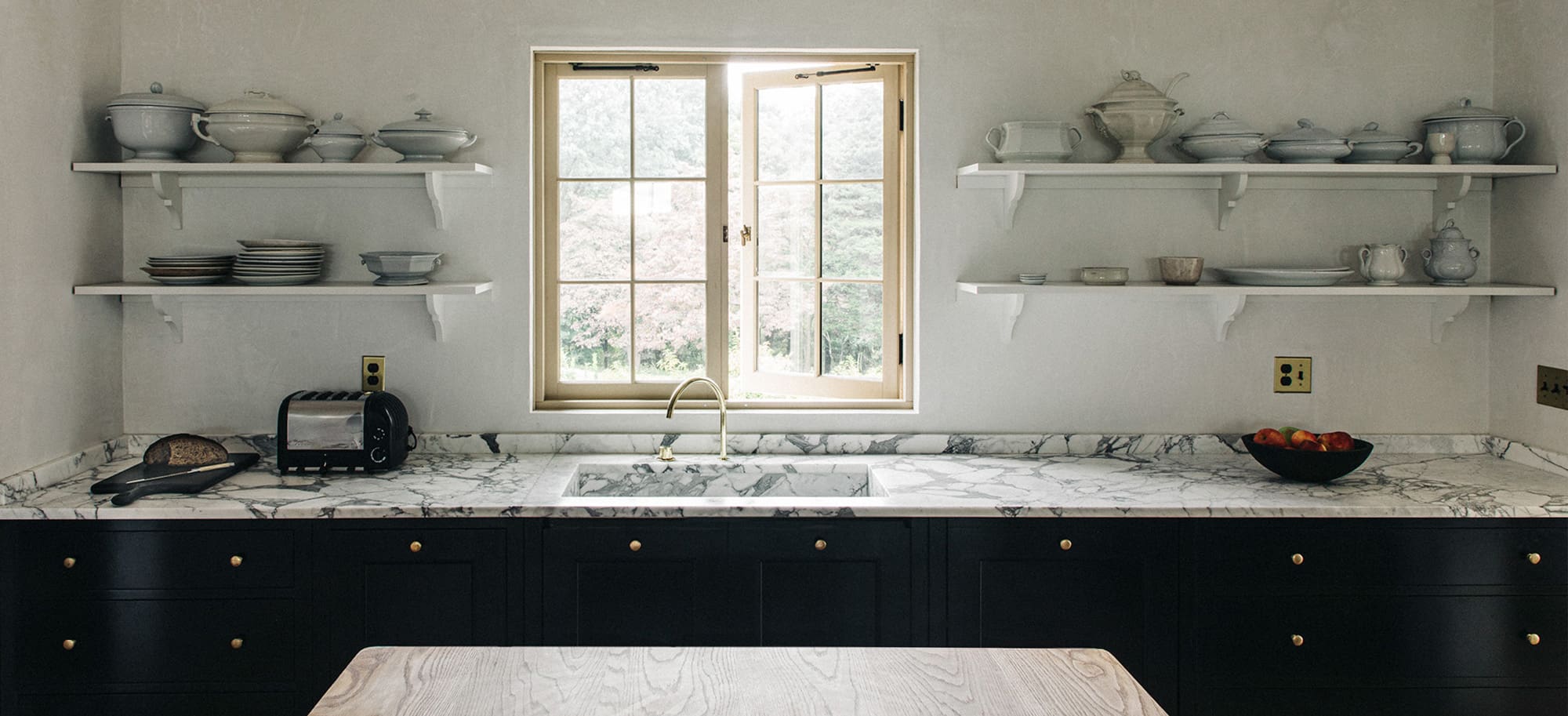  View of white marble countertops with black cabinetry and window