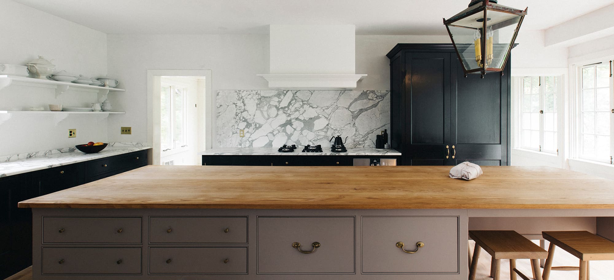 Full view of kitchen with wood island, black cupboard and white marble countertops