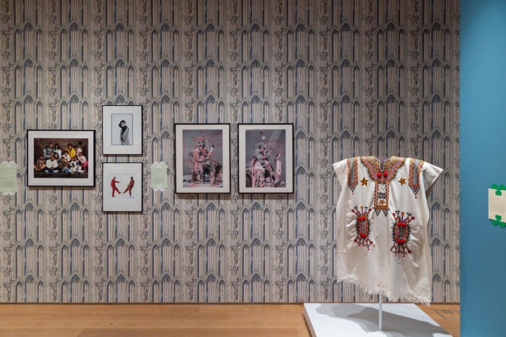 Framed art pieces on a wall covered in a beige and blue patterned wallpaper.