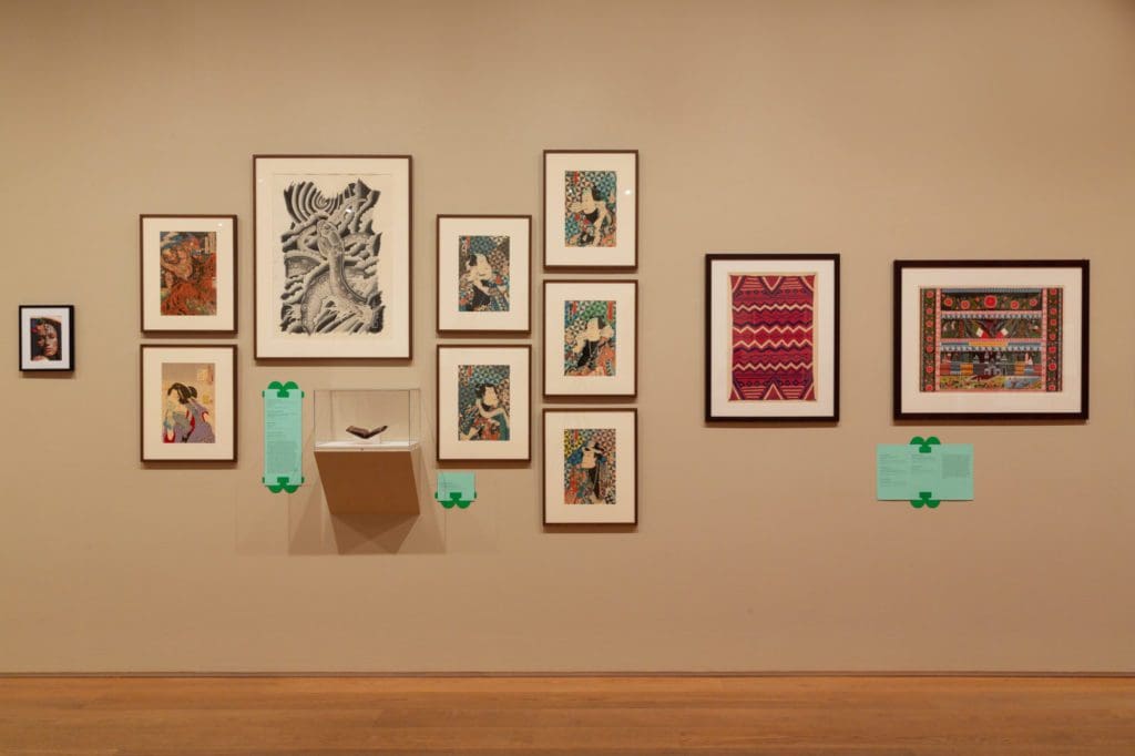 Framed art pieces covering a tan coloured wall.