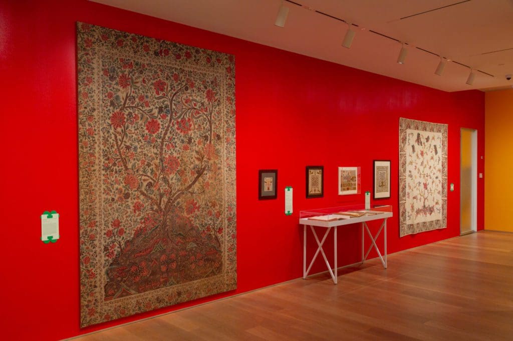 Large art pieces hanging along a red wall.