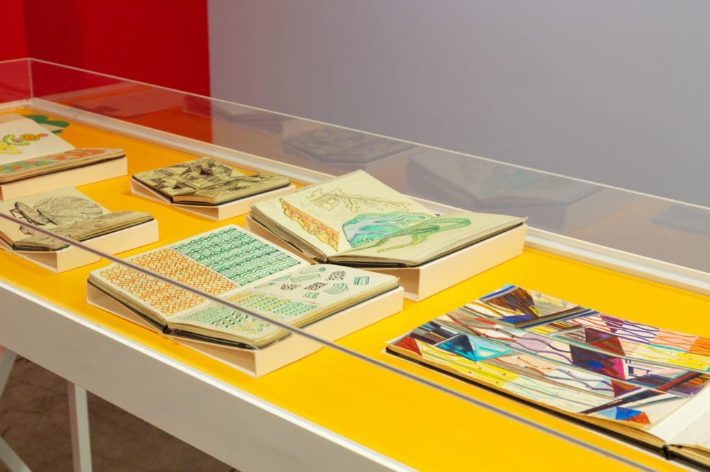 Close up of a white drawing table with yellow surface, covered in books.