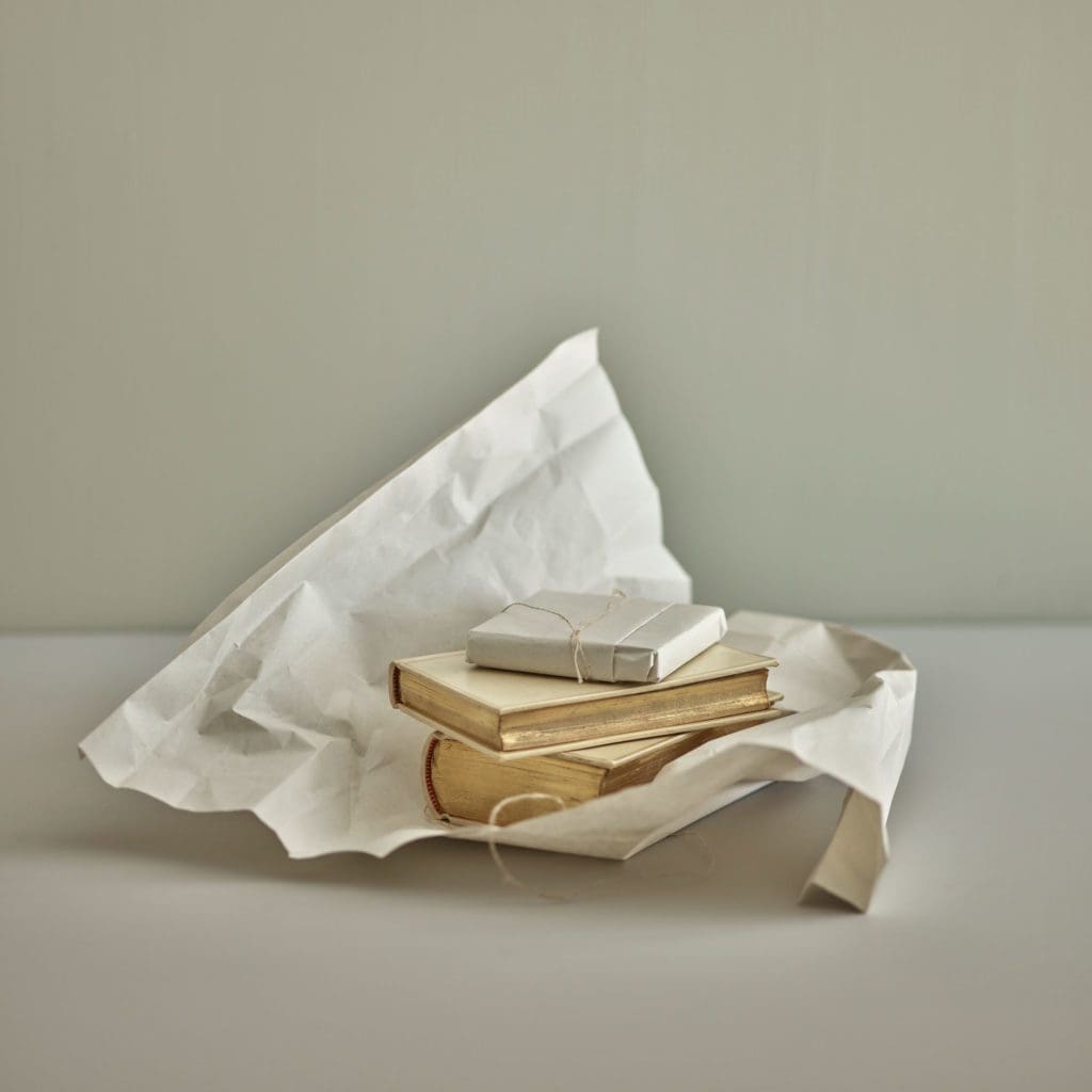 Small stack of books inside white wrapping paper.