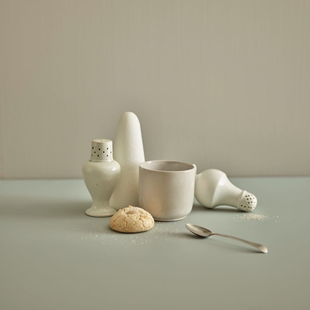 Close up of white kitchen accessories, including a spilled salt shaker.