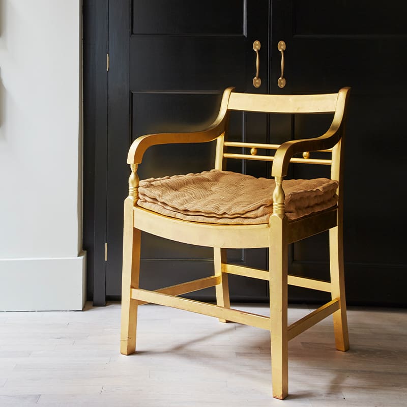 Close up of a wood chair in front of custom designed black cabinets.