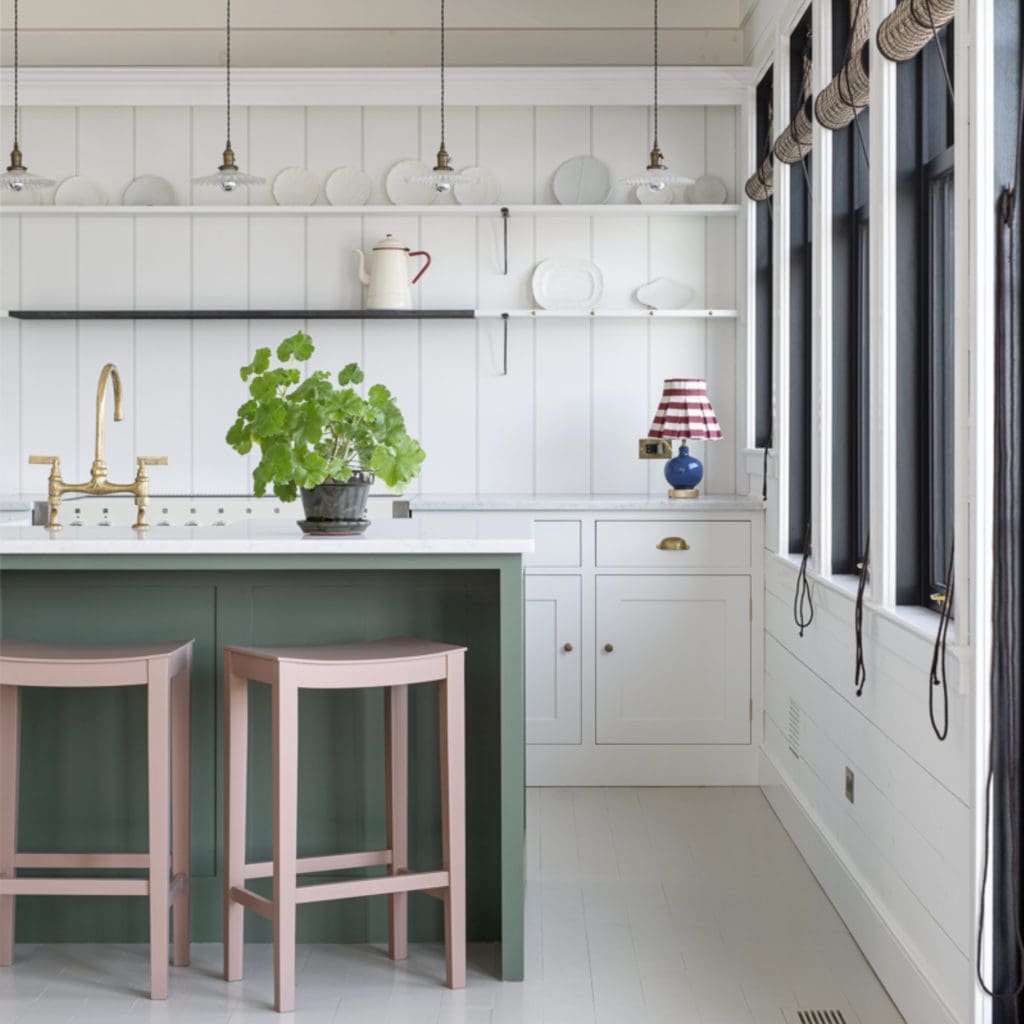 Green kitchen cabinetry with marble countertops, brass hardware, and a handmade copper sink.