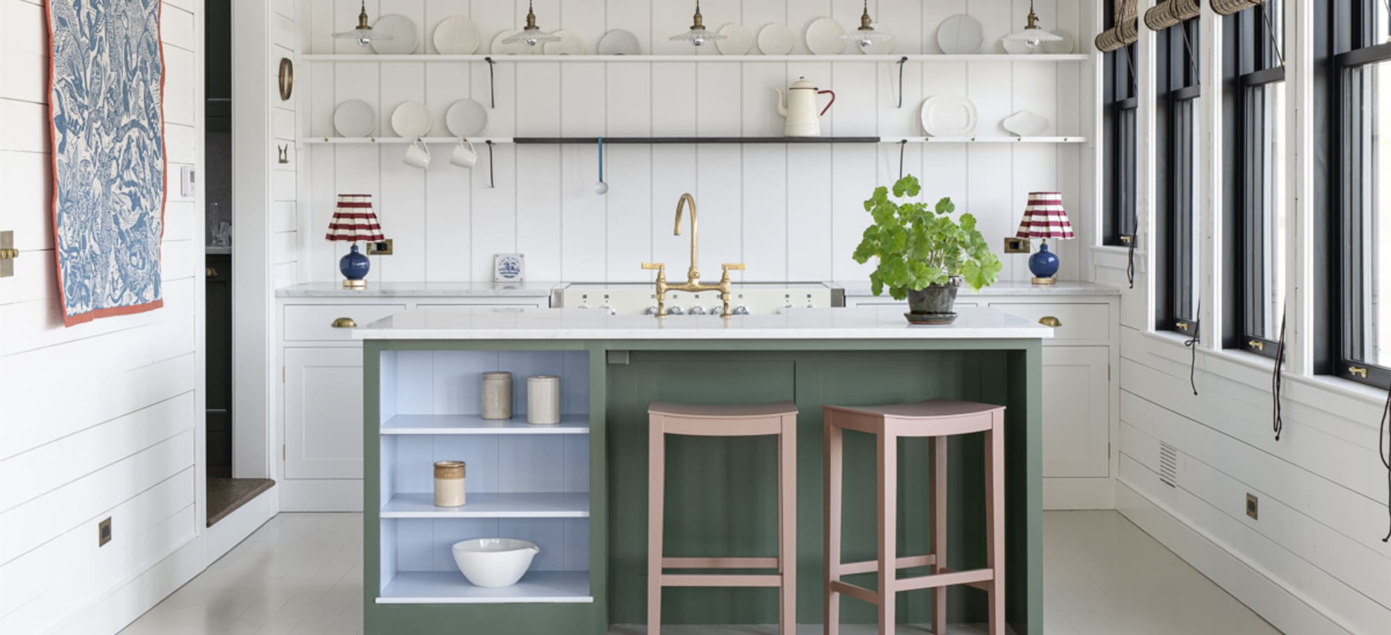  Sunlit Lakeside Cottage kitchen with a green island, pink stools, brass fixtures, and open shelving.