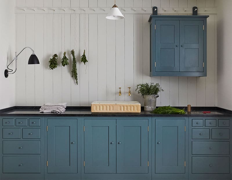 Custom designed blue cabinetry under a dark worktop surface.