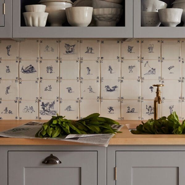 Close up of a sink with wooden countertops and a custom designed delft tile backsplash.