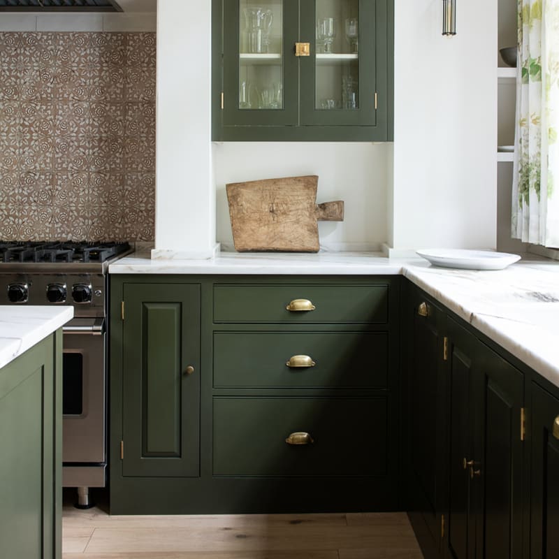 Modern bespoke kitchen featuring white tiled walls, black countertops, and custom cabinets in a bright green.