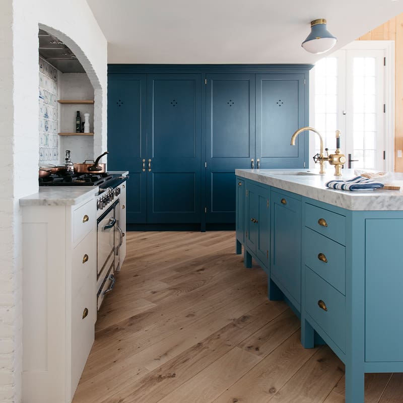 Custom kitchen with white cabinetry to the left and custom blue cabinets on the right and far wall.