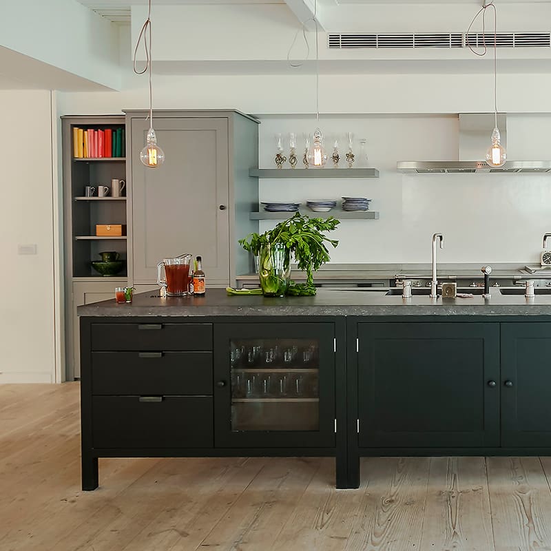 Custom designed kitchen island with dark cabinetry and a light coloured pantry in the background.