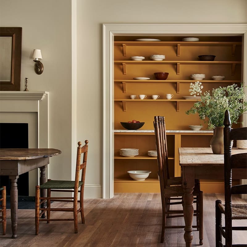 View of a custom designed pantry through a dining area with tables on both sides.
