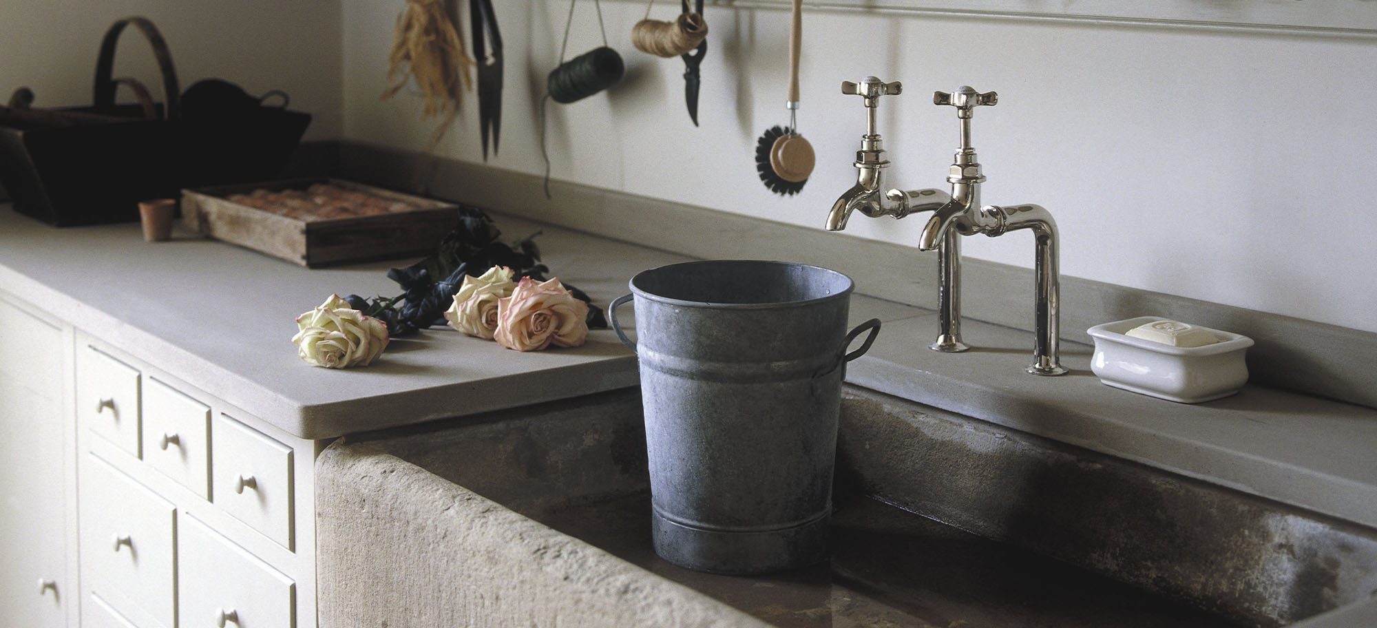 Stone sink with white cabinets and drawers in a custom, bespoke mudroom. 