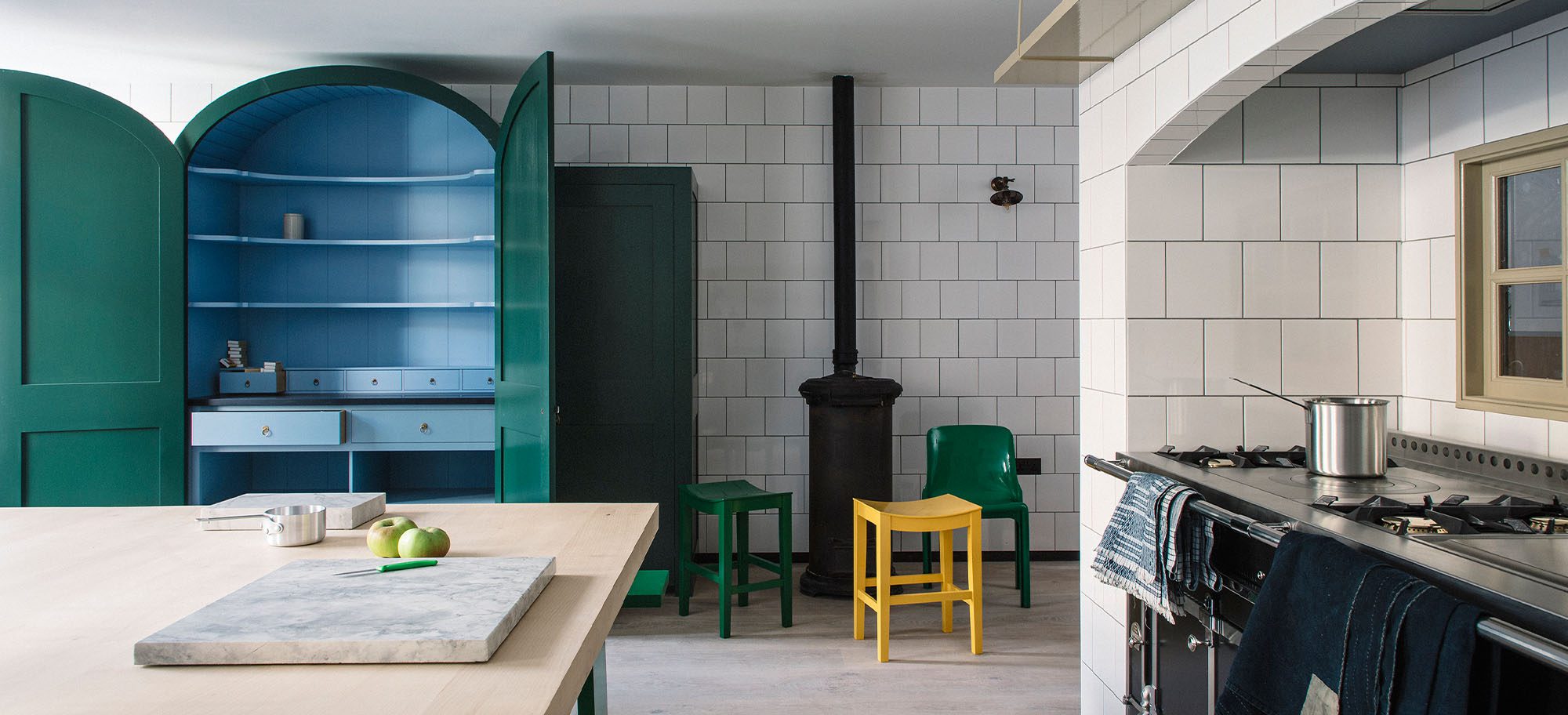 Custom kitchen design feautring a bespoke green pantry with blue shelving. 