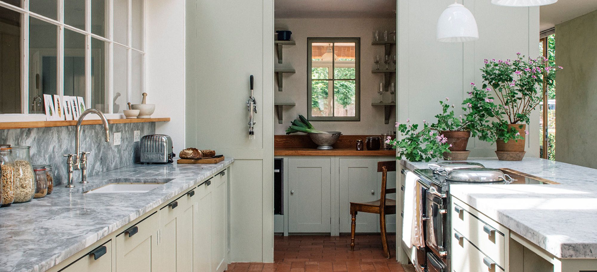 Bespoke kitchen featuring custom, light-coloured cabinets and marble countertops. 