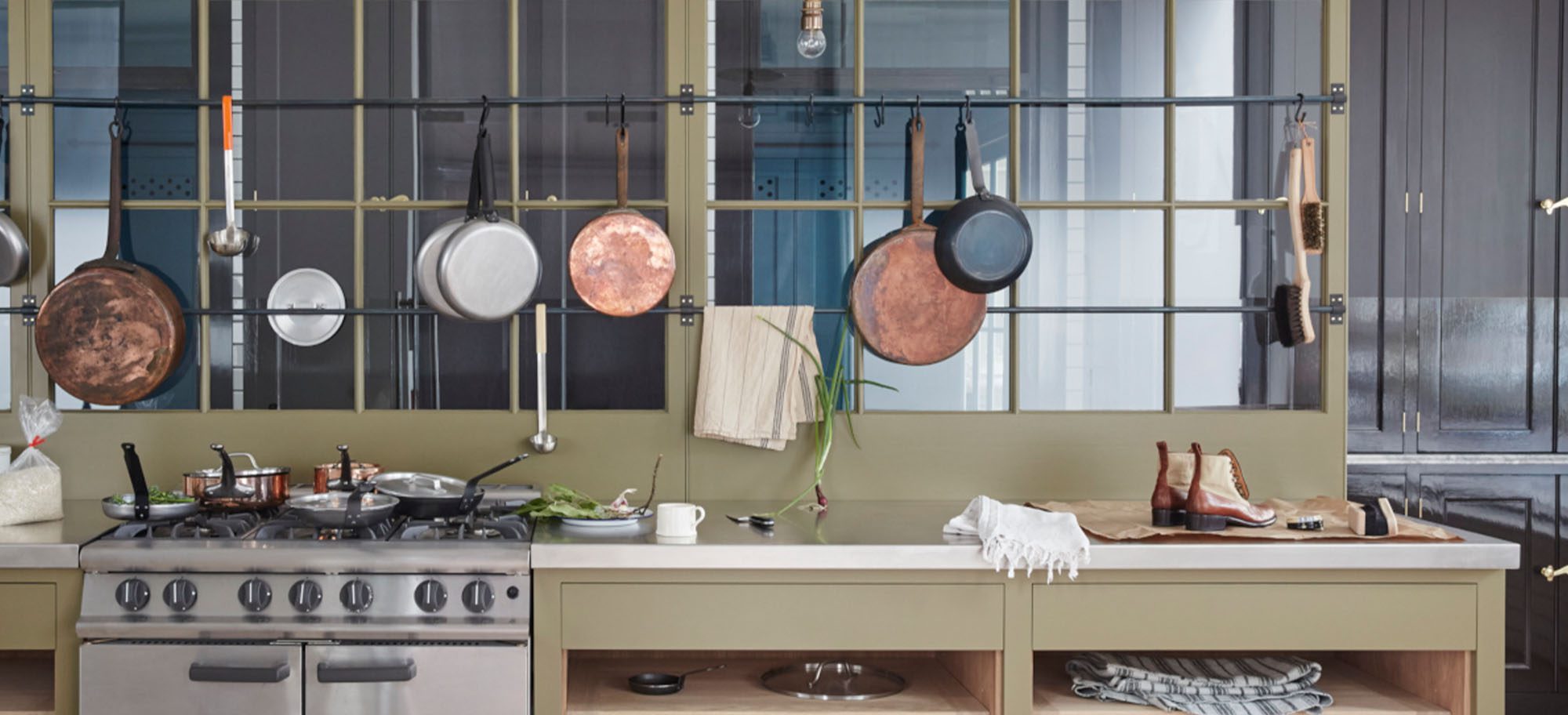 Pots and pans hanging along a custom designed kitchen, featuring neutral-coloured cabinets. 