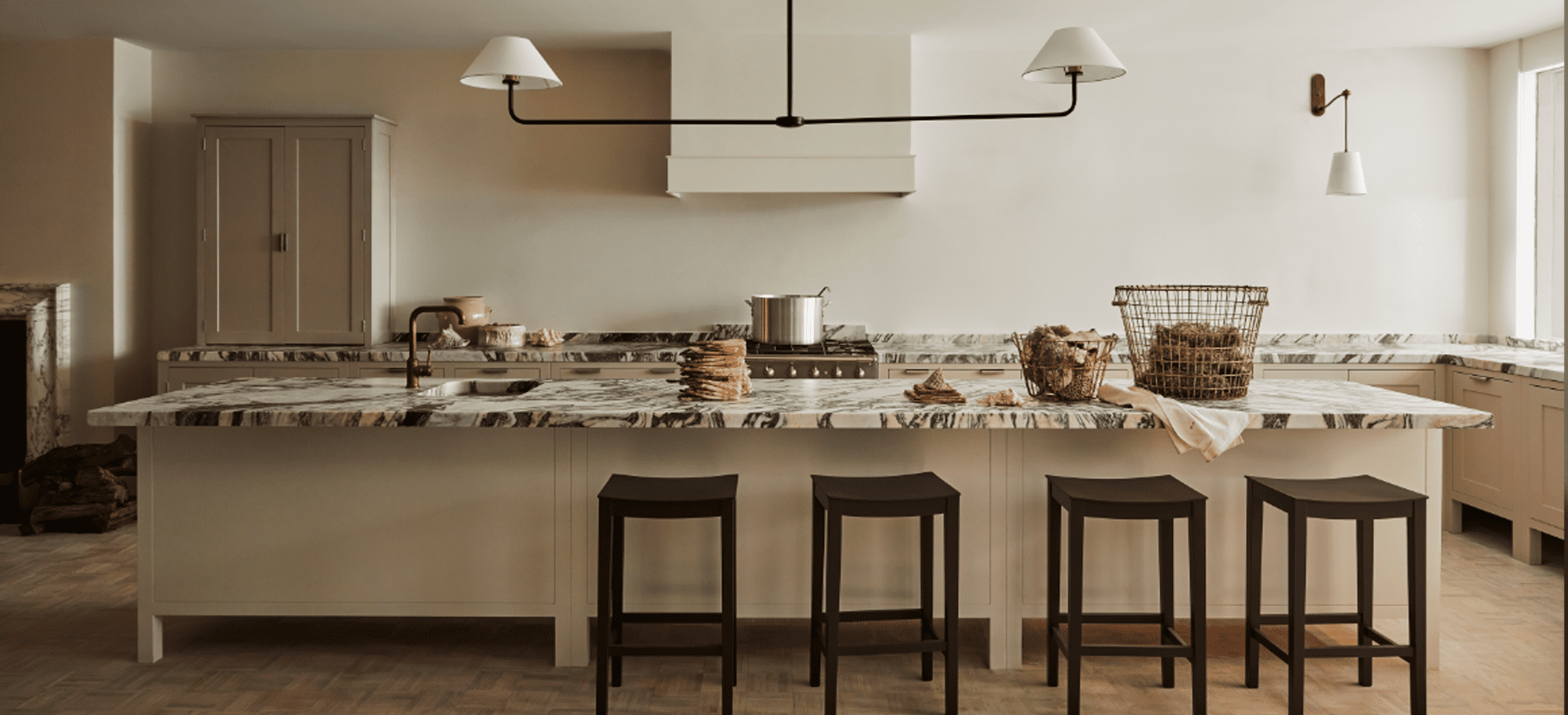  Bespoke kitchen design featuring a large island with black stools and custom beige cabinets throughout.
