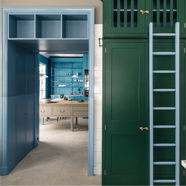 Custom cabinetry featuring green and blue cabinets with brass handles and a matching ladder.