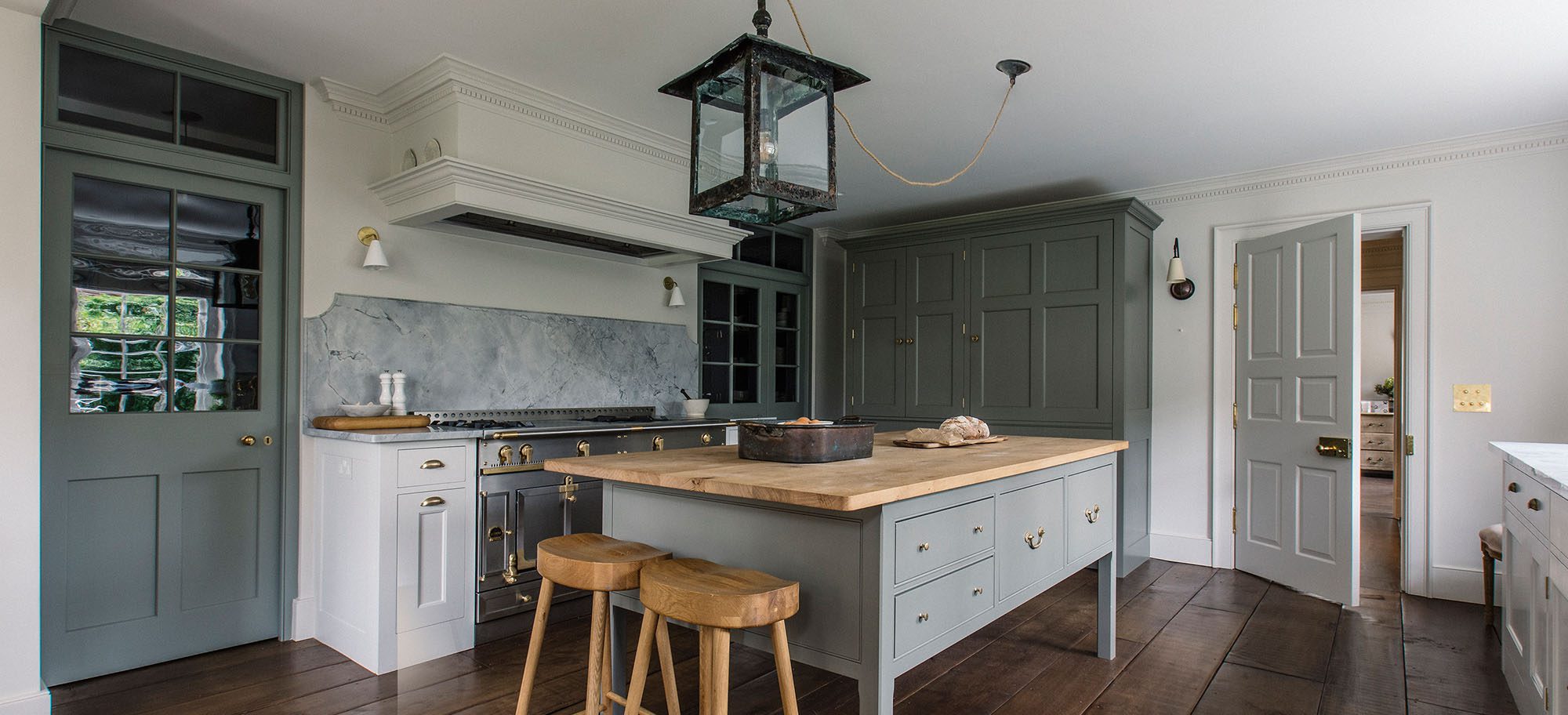  Luxury bespoke kitchen with parchment-painted cabinetry, Pippy Oak island, and marble worktops.