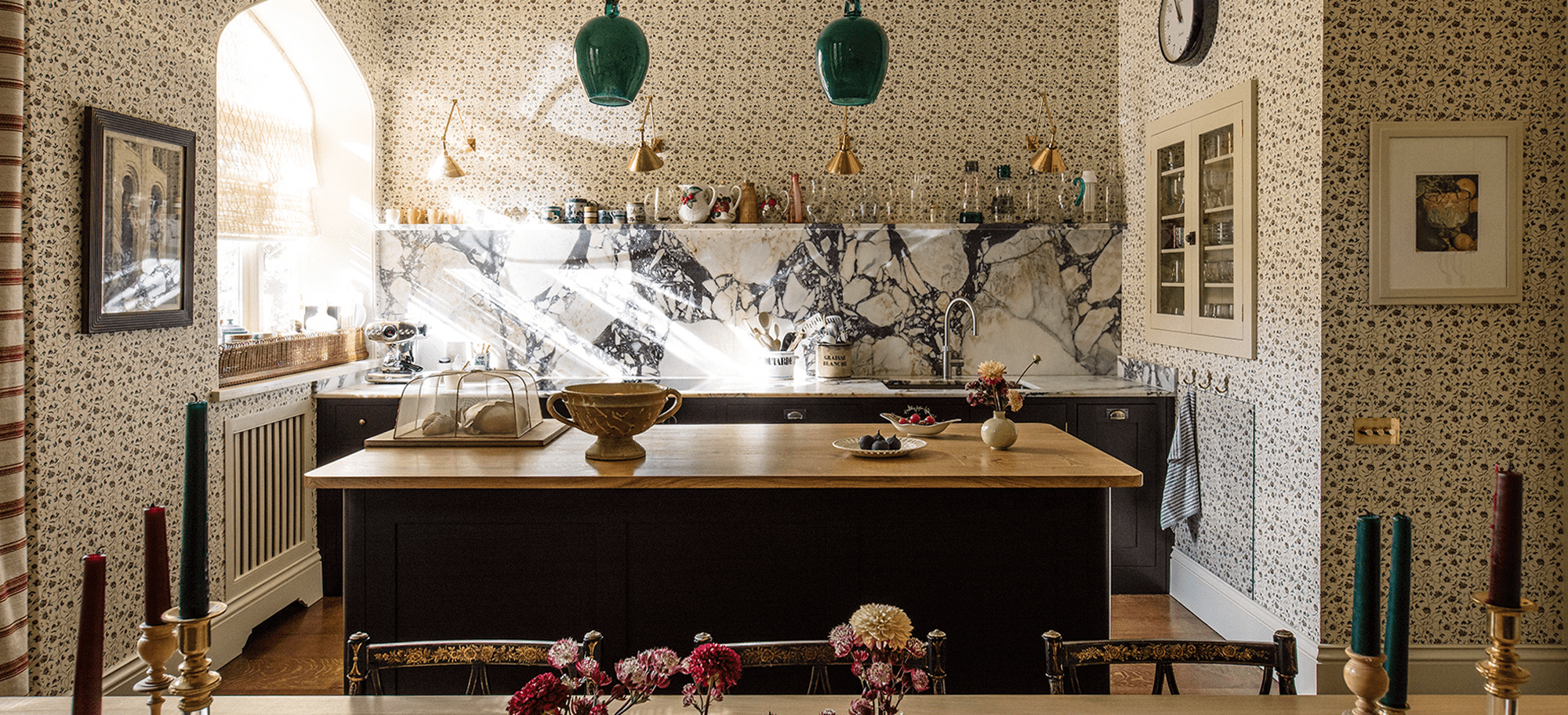  Kitchen featuring dark cabinets Calacatta Viola marble backsplash, brass pendant lighting, and central wooden island with decoratiations.