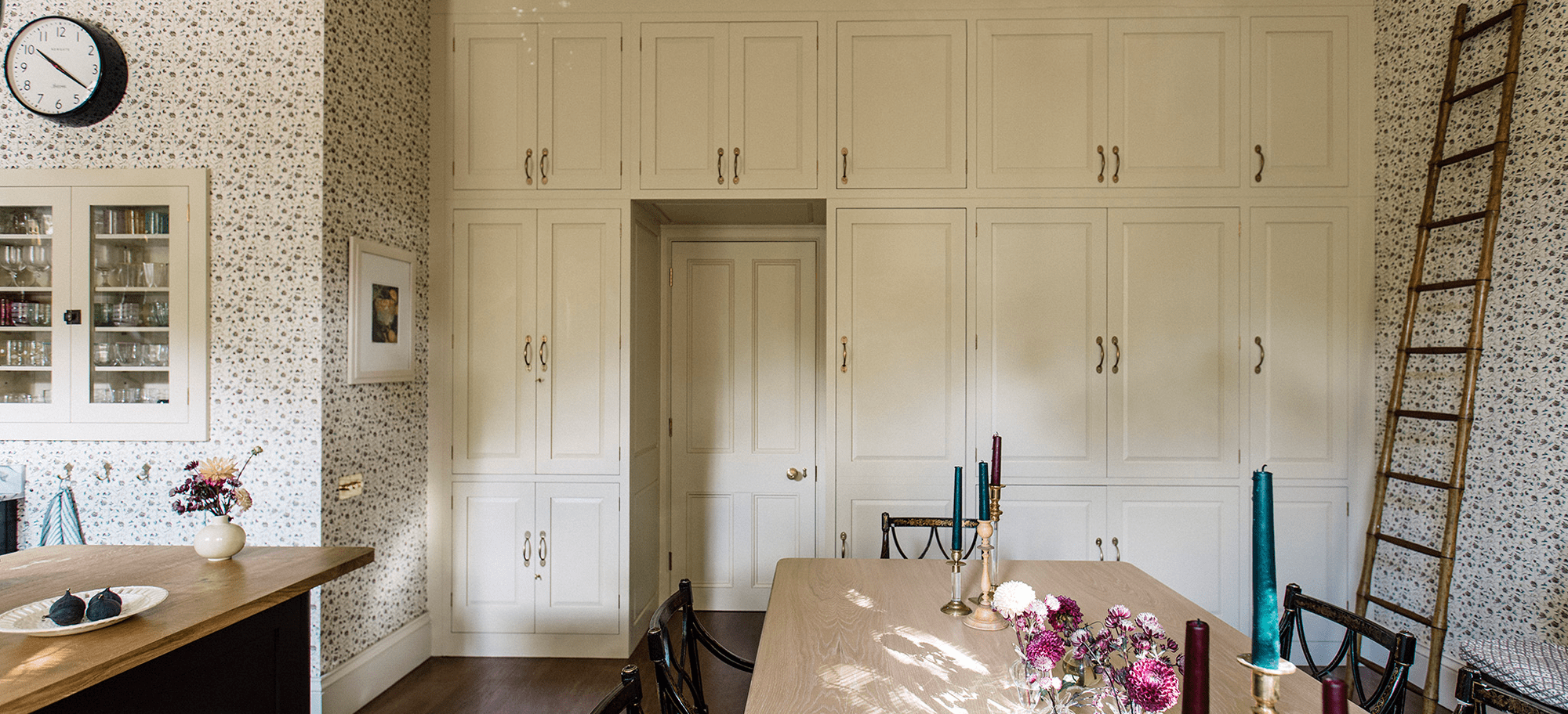  Kitchen with floor-to-ceiling Hanbury cupboards painted in ‘Flummery,’ antique brass handles, and floral wallpaper.