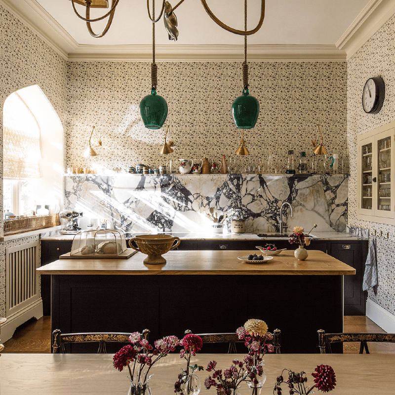Bespoke kitchen and dining area with dark cabinets and flowered wallpaper.
