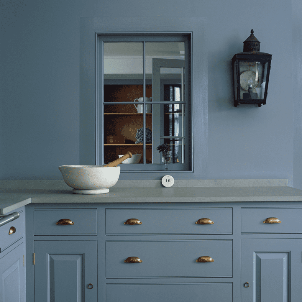 Bespoke blue cabinetry with brass handles, featuring a white countertop and decorative bowl.