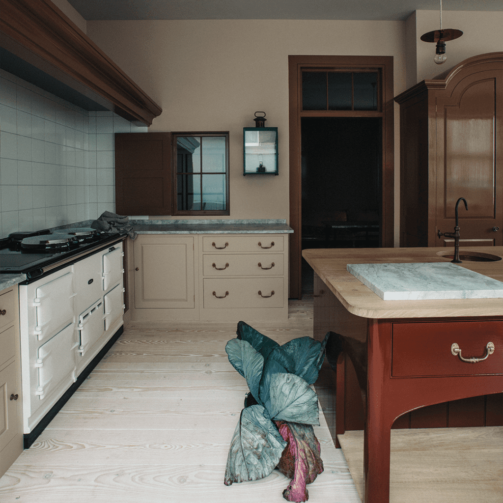 Kitchen with bespoke cabinetry in cream and marble countertops, featuring a classic stove and brass fixtures.
