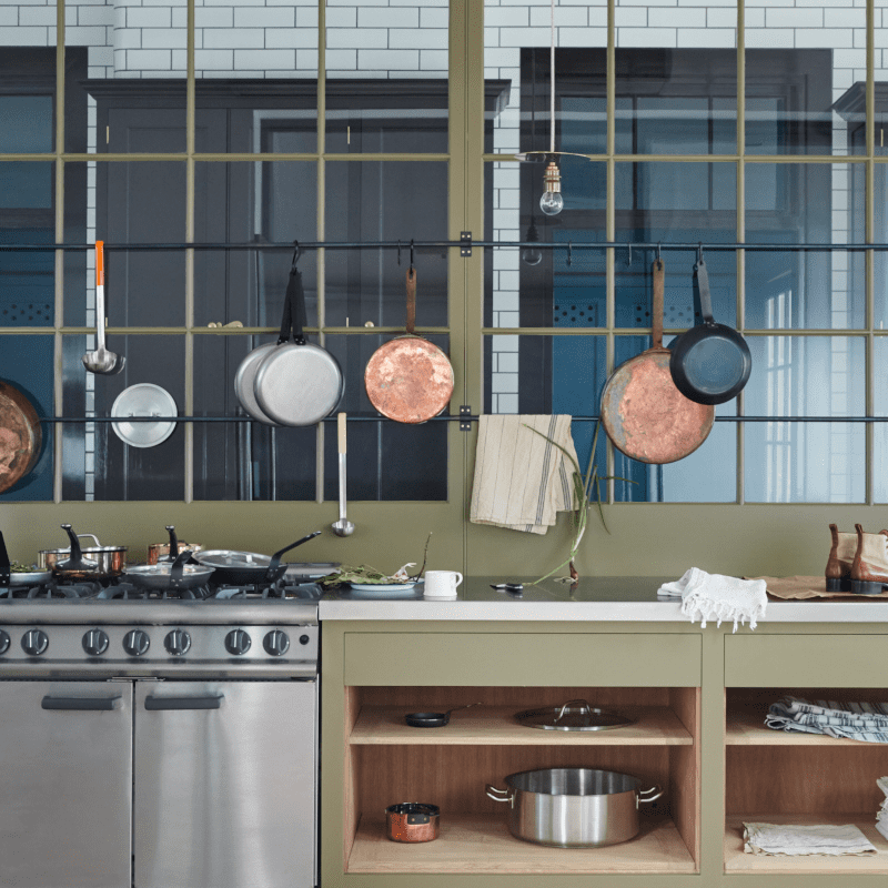 Bespoke cabinetry with olive green finish, featuring glazed screens and open shelving.