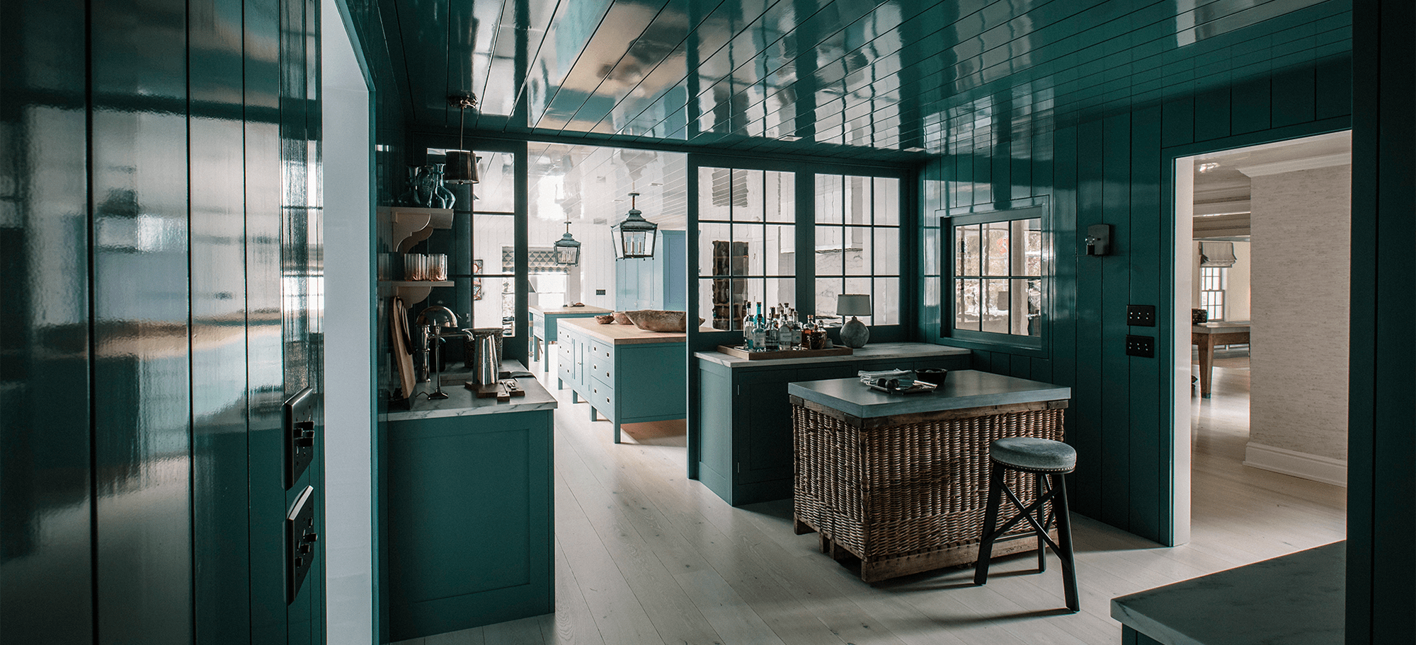  Bespoke cabinetry in rich teal, featuring custom shelving and a central island with a wicker base.