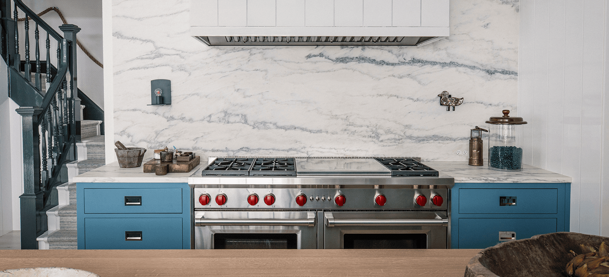  Kitchen featuring custom cabinetry with blue drawers, marble countertop, and stainless steel appliances.