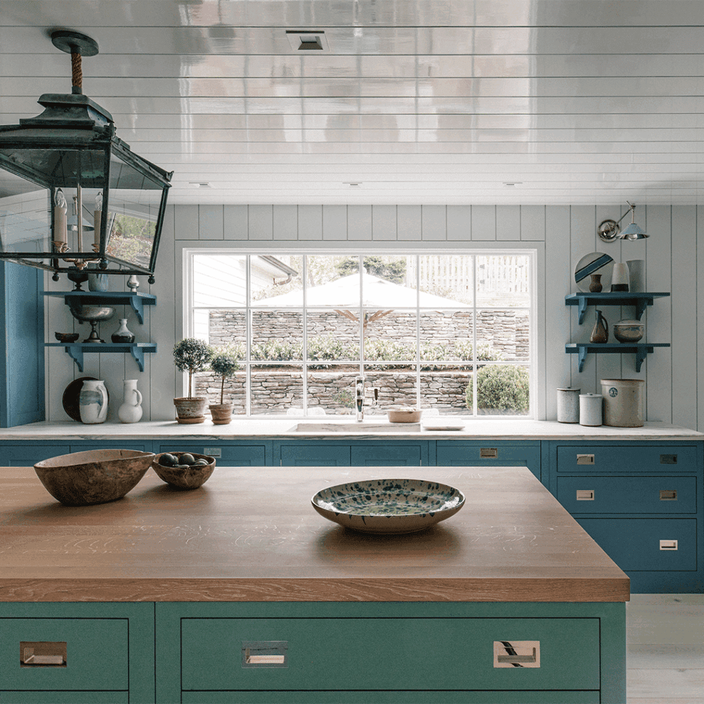 Bespoke cabinetry in teal and blue with a wooden countertop, featuring drawers and shelves.