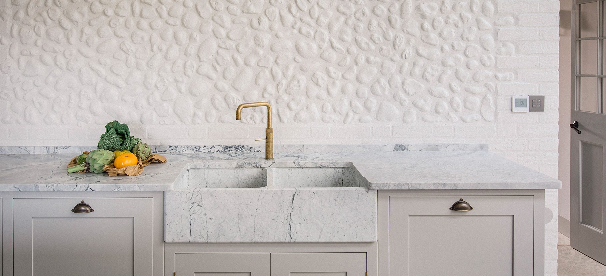  Light grey bespoke cabinets surrounding a marble sink.