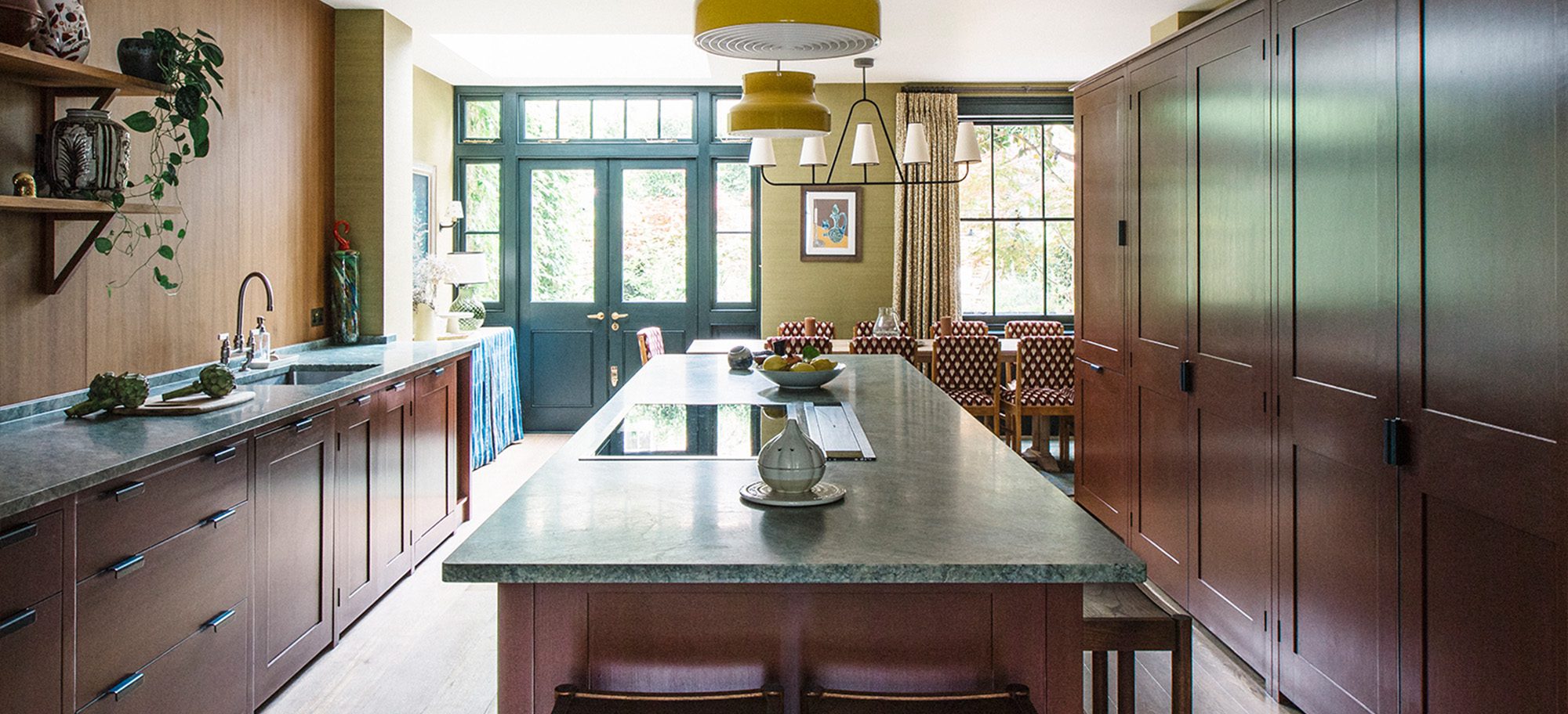  Kitchen with bespoke cabinets in rich brown with custom green marble countertops. Large island with integrated cooktop.