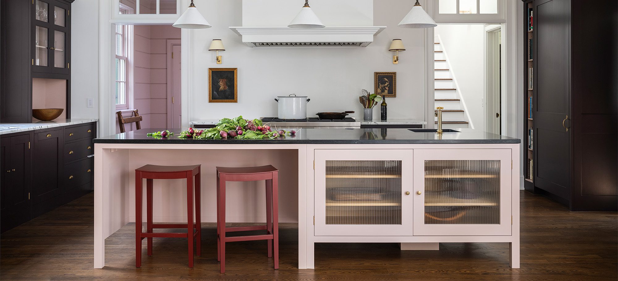  a bespoke kitchen with English cupboards in a light pink color and a large central island with seating