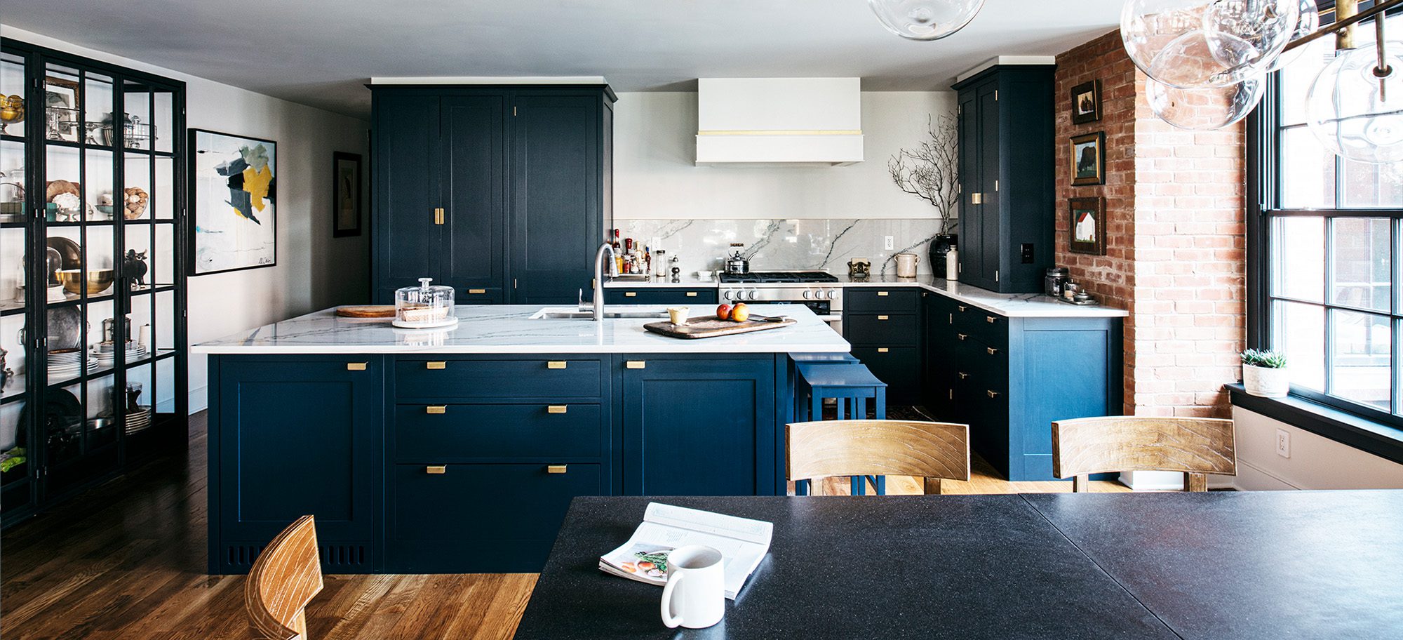  a custom kitchen with deep, navy blue cabinetry and gold-toned pulls, with a white-gray quartz countertop