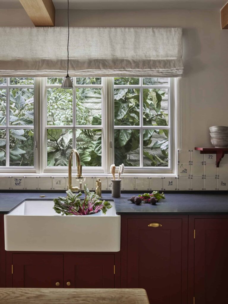 a kitchen sink with cabinets painted a dark red color called 