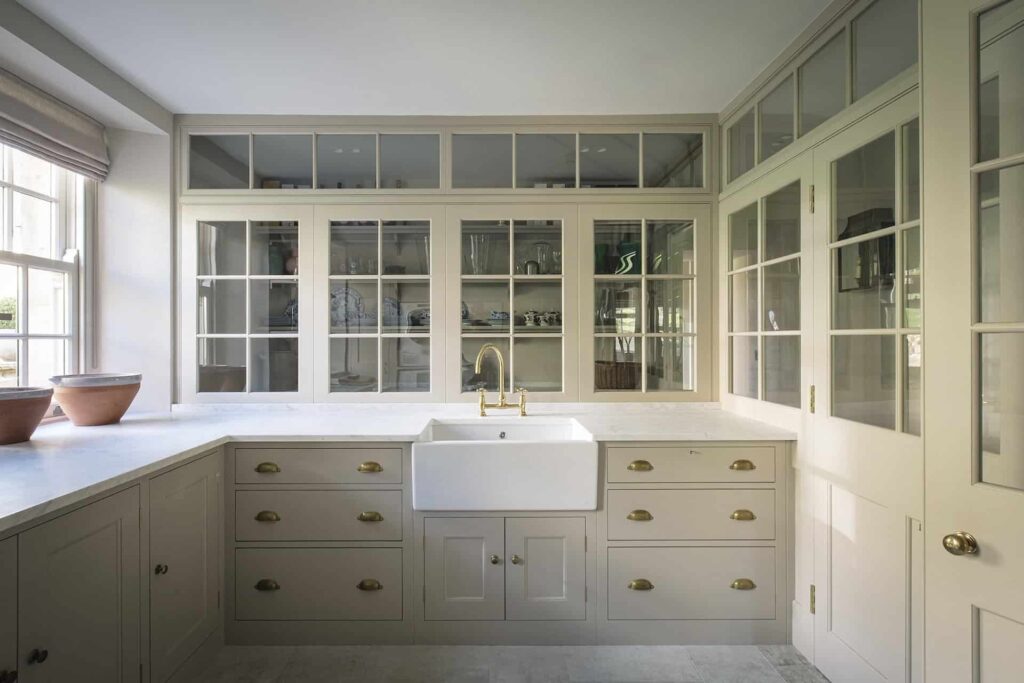 a bespoke kitchen with hand-painted cabinets in a pale gray with brass fixtures.