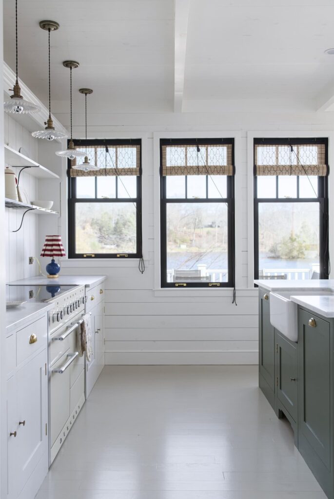 a modern farmhouse kitchen with custom white cabinetry and a sage green island with a farmhouse sink with white, stone countertops