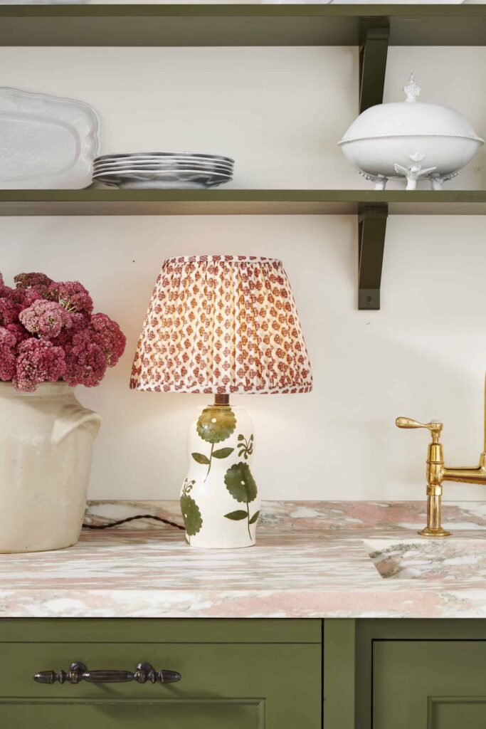 a Nickey Kehoe Rebekah MIles green floral table lamp on a pink and white quartzite countertop with a rich, olive green color