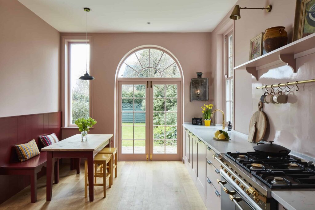 a kitchen-space with creamy pink walls, high ceilings, and contemporary styled cabinetry