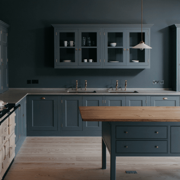 A kitchen with blue cabinetry, wooden countertops, and a light wood floor, featuring classic Georgian-inspired design elements.