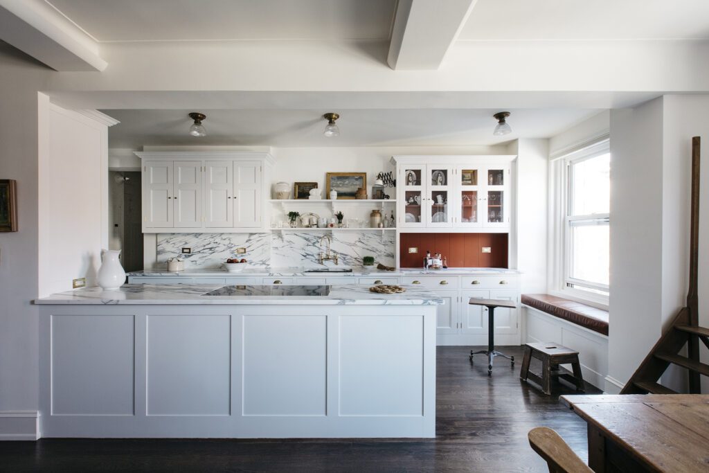 Open floor plan kitchen with bespoke white cabinetry and marble countertops