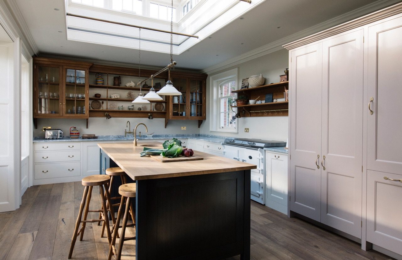  a classic, welcoming kitchen with a large central island with a dark base and wooden top, open shelving, with painted and natural wood cabinetry